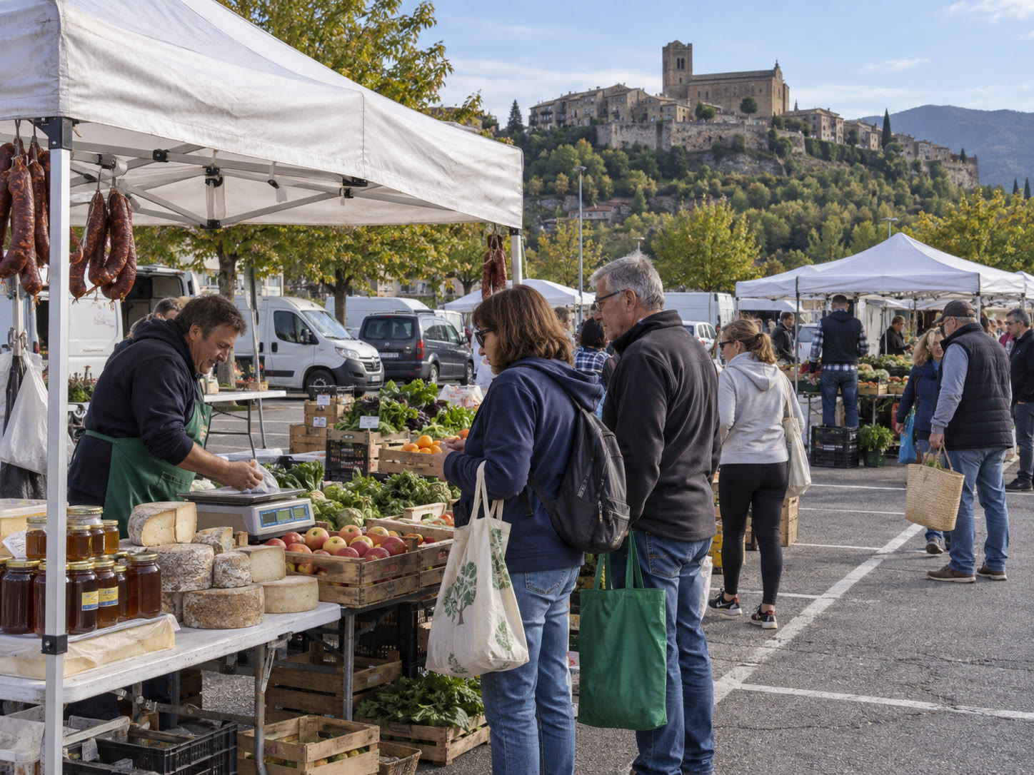 Étals du marché du mardi sur le parking d’Aínsa, avec la cité médiévale en hauteur